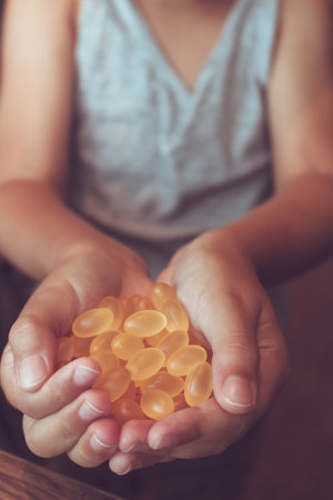 Close up of kid with hand full with omega 3 pills.の写真素材