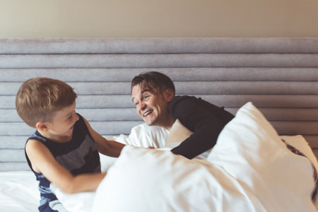 Happy father and son having fun while playing on the bed.の写真素材