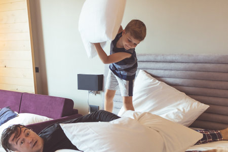 Playful boy and his father pillow fighting at home.の写真素材
