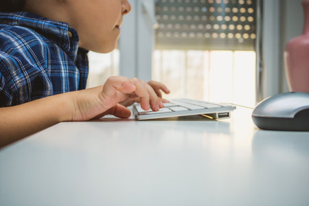 Close up of kid using computer and typing on keyboard. Copy space.の写真素材