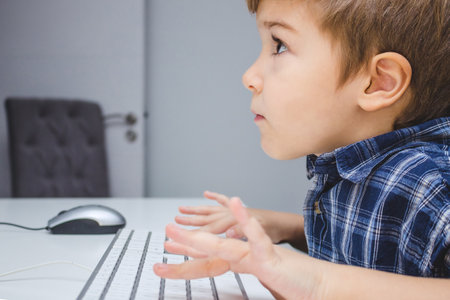 Focused kid playing games on computer at home.の写真素材