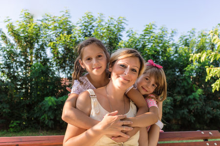 Portrait of happy daughters embracing their mother.