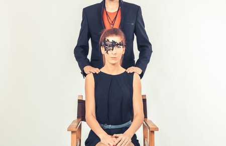 Redhead woman wearing black mask while unrecognizable man is standing behind her.の写真素材