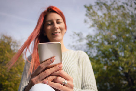 Close up of woman using mobile phone and surfing the net in nature.の写真素材