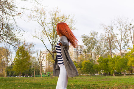 Carefree woman turning around with arms outstretched in the park.の写真素材