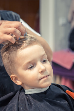Small kid enjoying at hairdresser's while getting new hairstyle.の写真素材