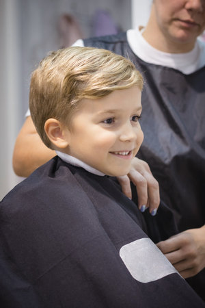 Cute small boy getting ready for haircut at hair salon.の写真素材