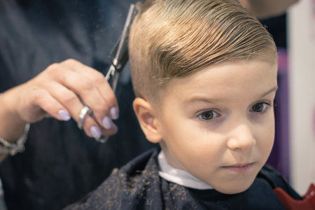 Pensive kid getting haircut at barber shop.の写真素材