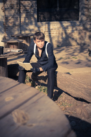 Mid adult man thinking of something while reading book outdoors.の写真素材