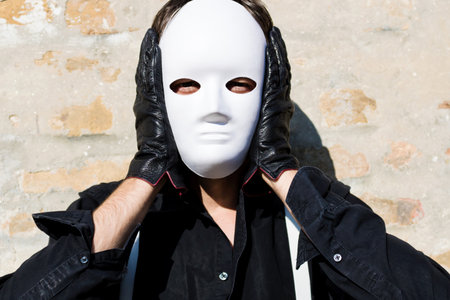 Portrait of a man with white mask on his face looking at camera.の写真素材
