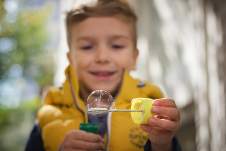 Close up of happy boy having fun and blowing soap bubbles.の写真素材