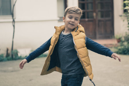 Playful boy turning around with eyes closed and arms wide open.の写真素材