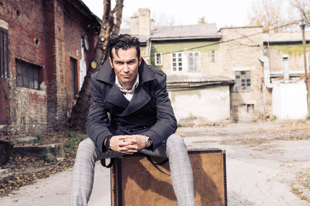 Pensive man sitting on a suitcase and thinking of his life journey.の写真素材