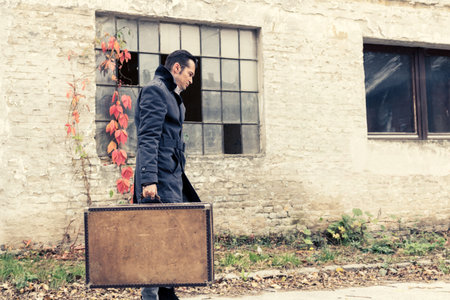 Pensive man walking with suitcase and thinking of something.の写真素材