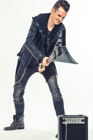 Aggressive musician smashing guitar amplifier with electric guitar on white background.の写真素材