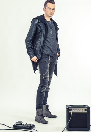 Portrait of hard rock musician standing next to music equipment on white background.の写真素材