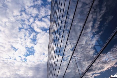 Sky and glass wall of an office building, reflections of clouds.