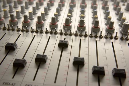 Professional audio mixing board with multiple channel faders and adjusting knobs