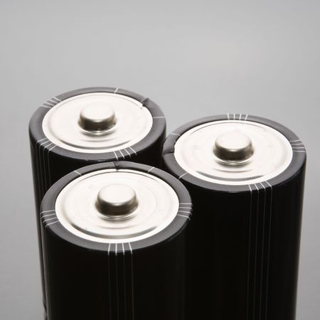 Three LR20 alkaline batteries on a reflective studio backgroundの写真素材