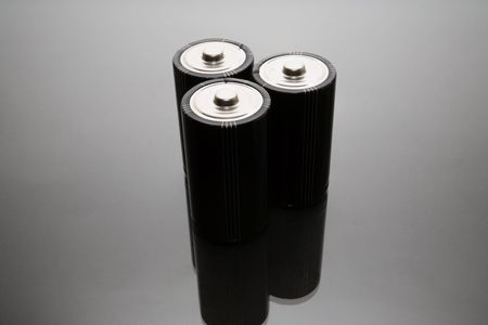 Three LR20 alkaline batteries on a reflective studio backgroundの写真素材