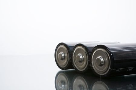Three LR20 alkaline batteries on a reflective studio backgroundの写真素材