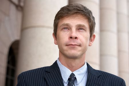 Portrait of man by colonnade pillars of building, wet eyes