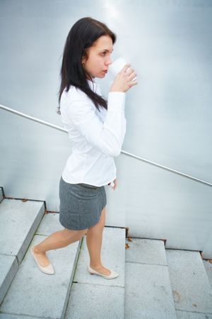 Young woman drinking coffee on stairsの写真素材