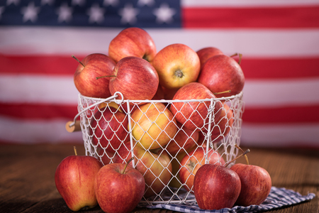 organic red apples in a metal mesh basket with american flag in a background  healthy diet weight loss conceptの写真素材