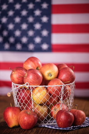 organic red apples in a metal mesh basket with american flag in a background  healthy diet weight loss conceptの写真素材