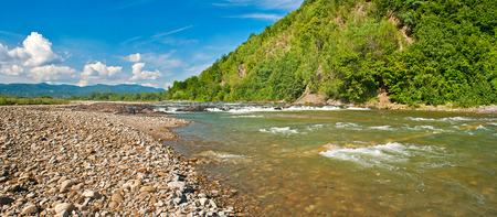 Mountain river near rocks growing with forestの写真素材