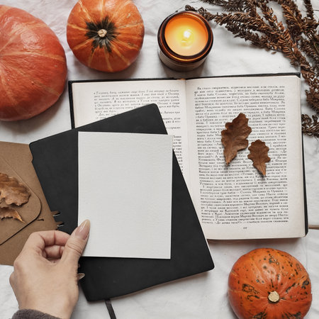 Blank postcard, book and pumpkins top view. Autumn artist workspace. Flat lay composition.の写真素材