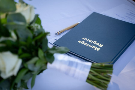 Marriage register book with bouquet and pen on table.の写真素材