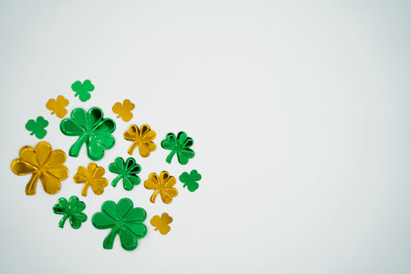 Top view of green and gold shamrock confetti isolated on white background with copy space.