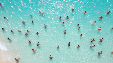 aerial shot of people swimming in the ocean near the beach on a sunny day, clear turquoise water viewの素材