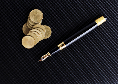 Fountain pen and coins stack on Leather  background for business conceptの写真素材