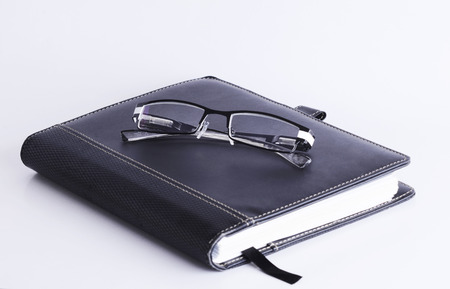 Eyeglass on Business memory Book Isolated on white background