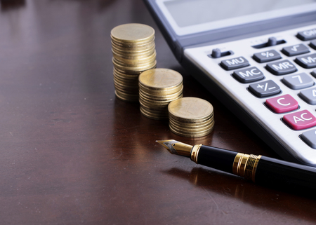 Fountain pen and Money coins stack and calculator for finance conceptの写真素材