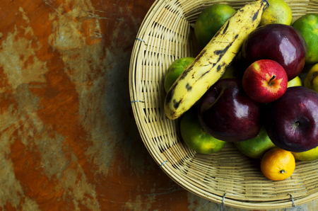 Still life fruts with apple banana and orange in basket weave on wooden table backgrounds above. Place for your textの写真素材