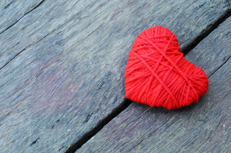 Red heart shape made from thread yarn on old wooden background for Valentines day conceptの写真素材