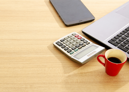 Red cup coffee and calculator and labtop and tablet on wood table backgroundsの写真素材