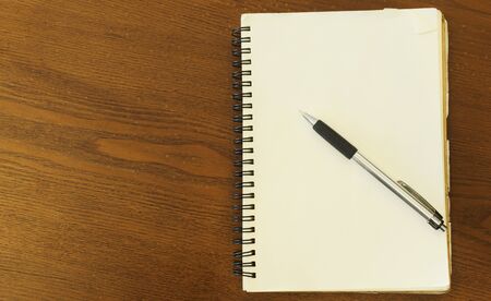Pen put on notebook blank page on wood table backgrounds above. Place for your textの写真素材