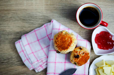 Close up of Scone homemade raisin  adn red cup coffee on wooden table backgrounds above, Top viewsの写真素材