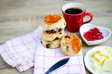 Close up of Scone homemade raisin  adn red cup coffee on wooden table backgrounds conceptの写真素材