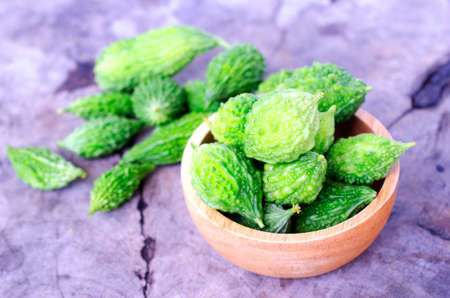 Close up of green bitter gourd vegetable raw food on vintage wood table backgrounds conceptの写真素材