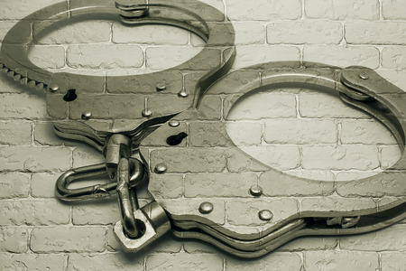 handcuffs on textured background of gray brick wallの写真素材