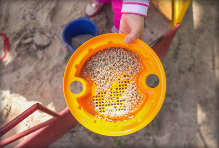 child holds a toy in a sandbox in the handの写真素材