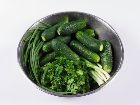 Fresh cucumbers and fresh herbs with drops in a bowl isolatedの写真素材