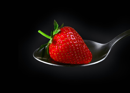 fresh strawberry on a silver spoon on a black background closeupの写真素材