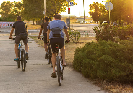 three sport Man riding a bike in the city at sunsetの写真素材