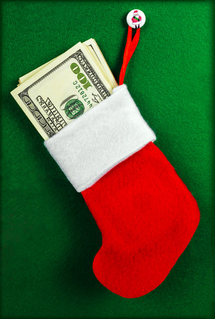 Christmas stocking full of hundred-dollar bills on the green backgroundの写真素材